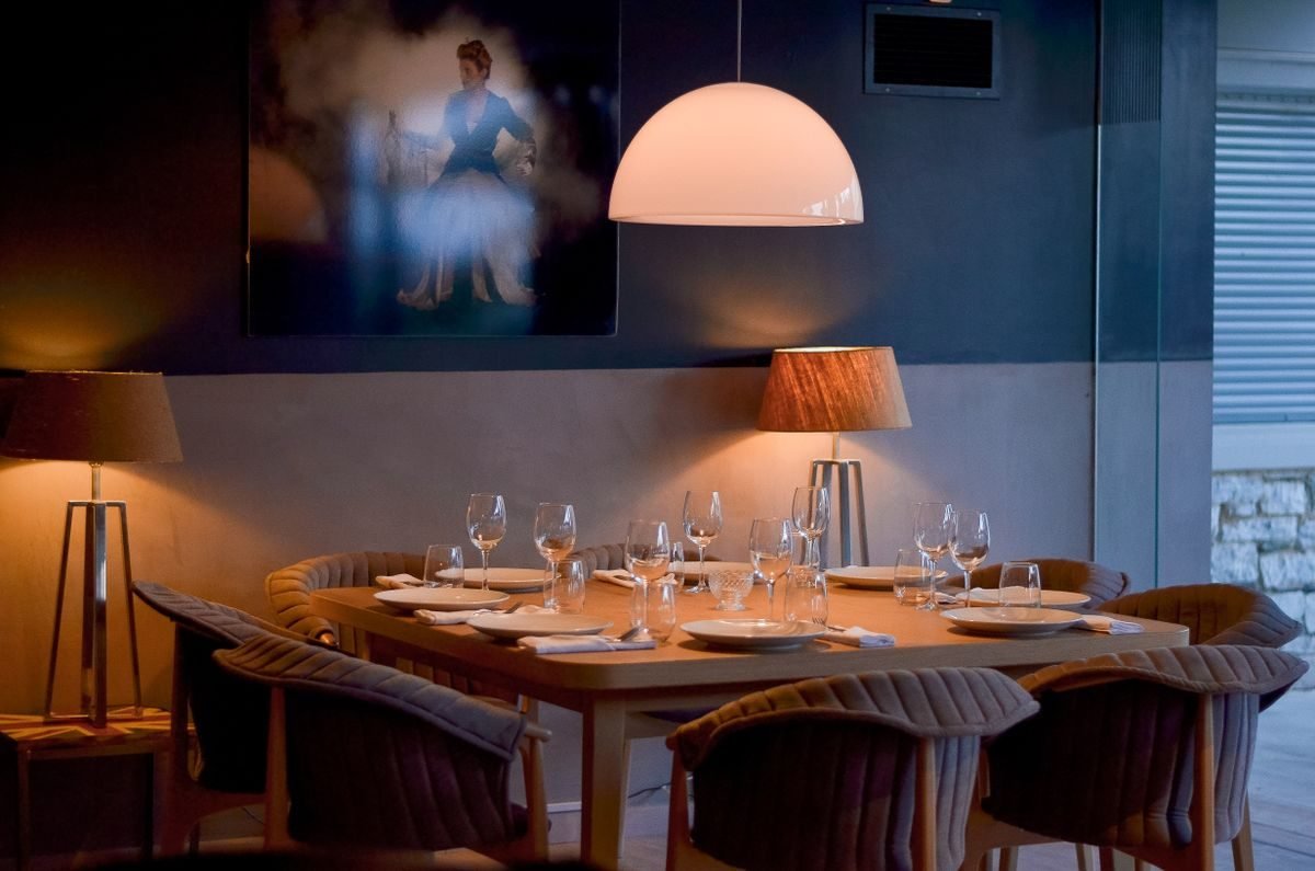 A warm candlelit restaurant dining room with a set table and wine glasses