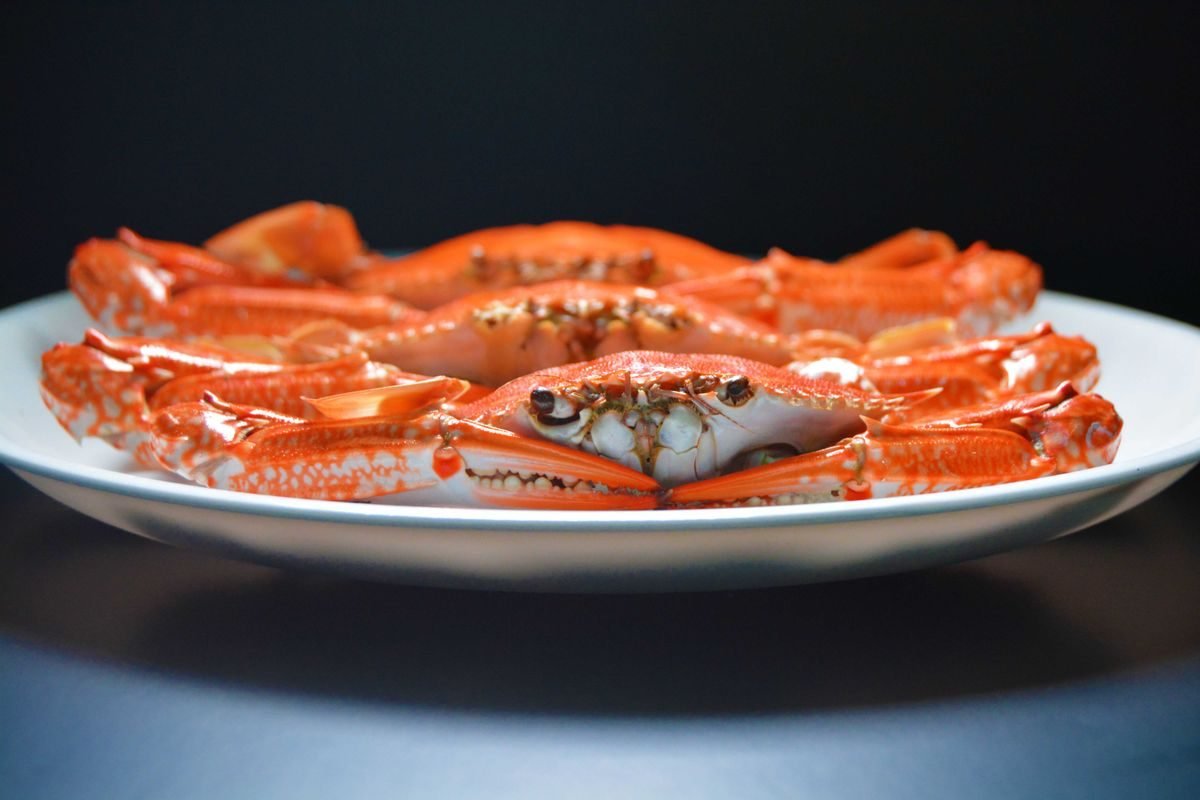 A plate of whole cooked crabs against a dark background