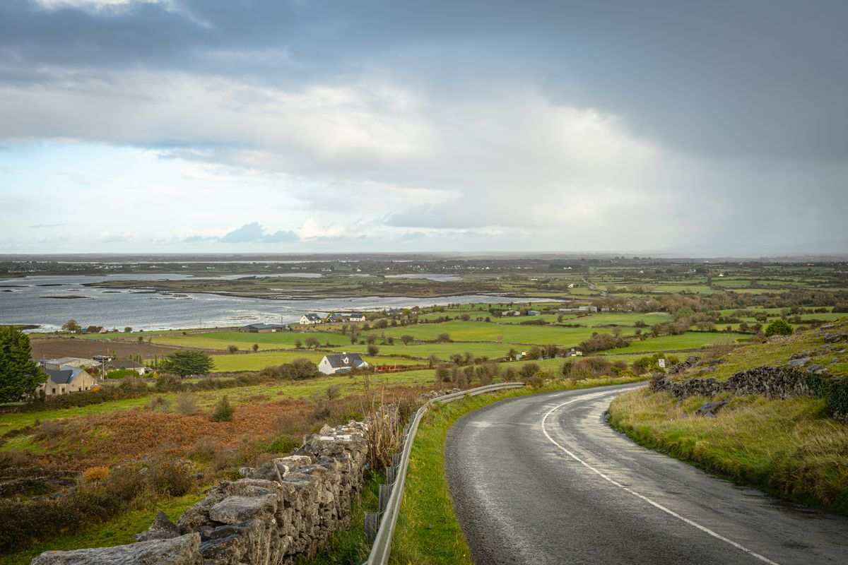 Rural road descending toward the coast and scattered cottages near Doolin in County Clare