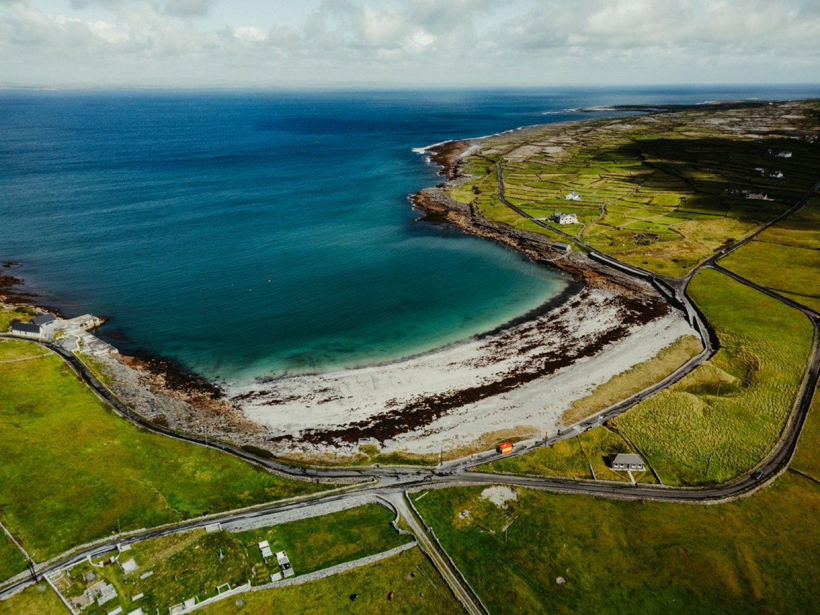 White-sand beach and turquoise bay on Inisheer ringed by stone-walled fields