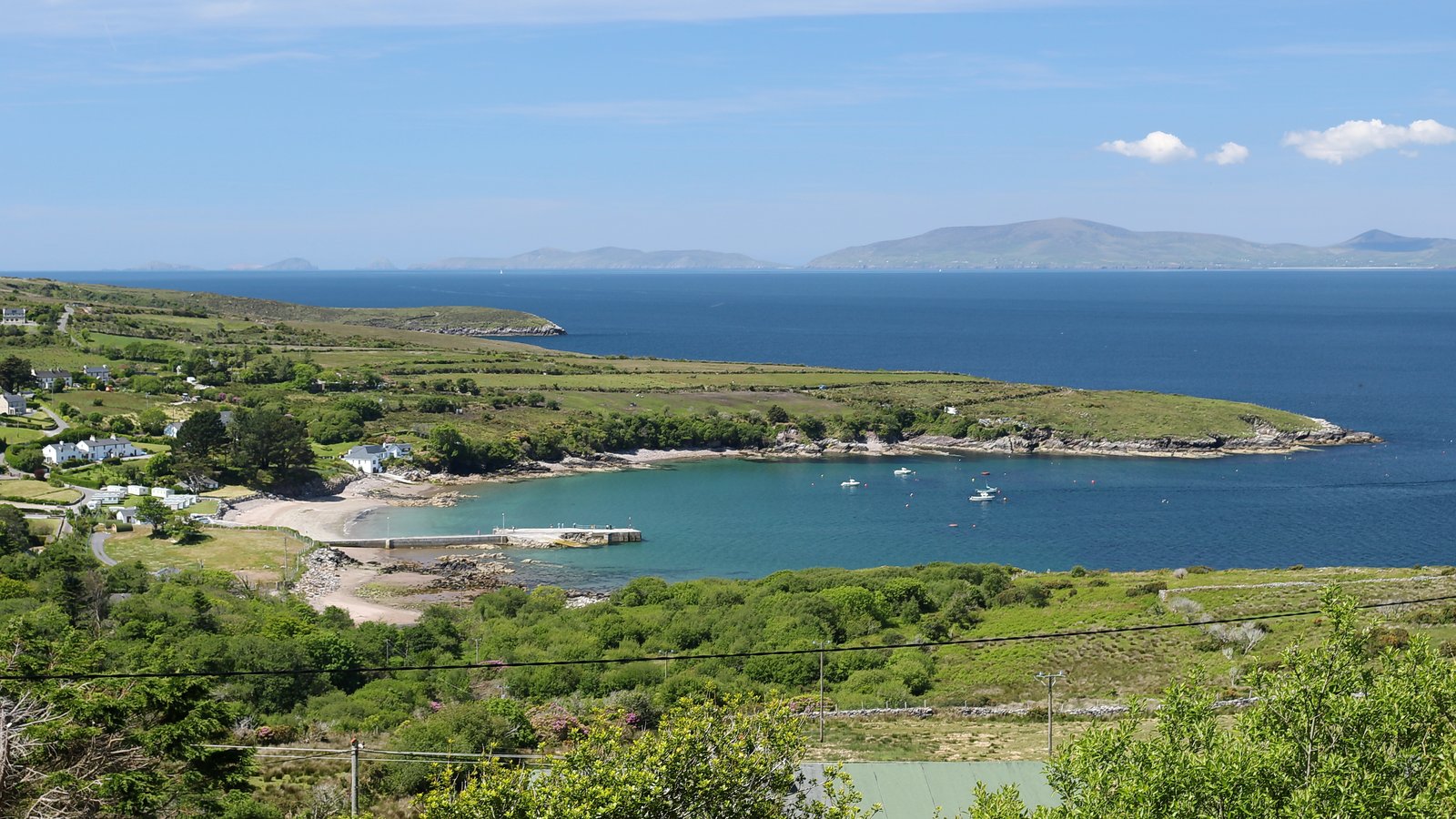 Sheltered cove at Kells below green hills with clear calm water