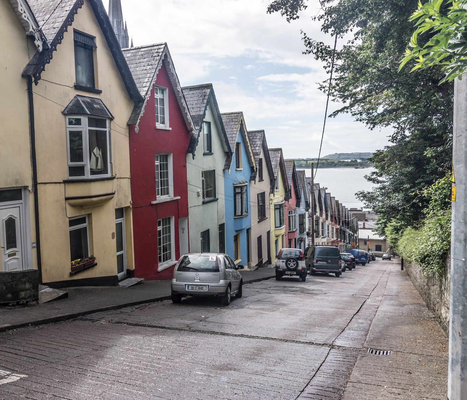 The Deck of Cards colourful terraced houses on a steep street in Cobh with the harbour behind