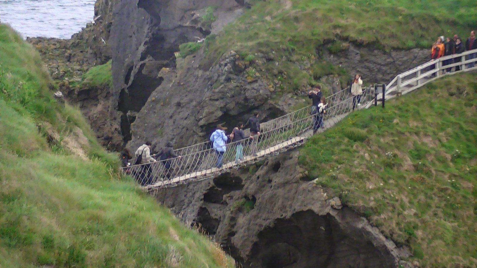 People crossing the Carrick-a-Rede rope bridge above the sea