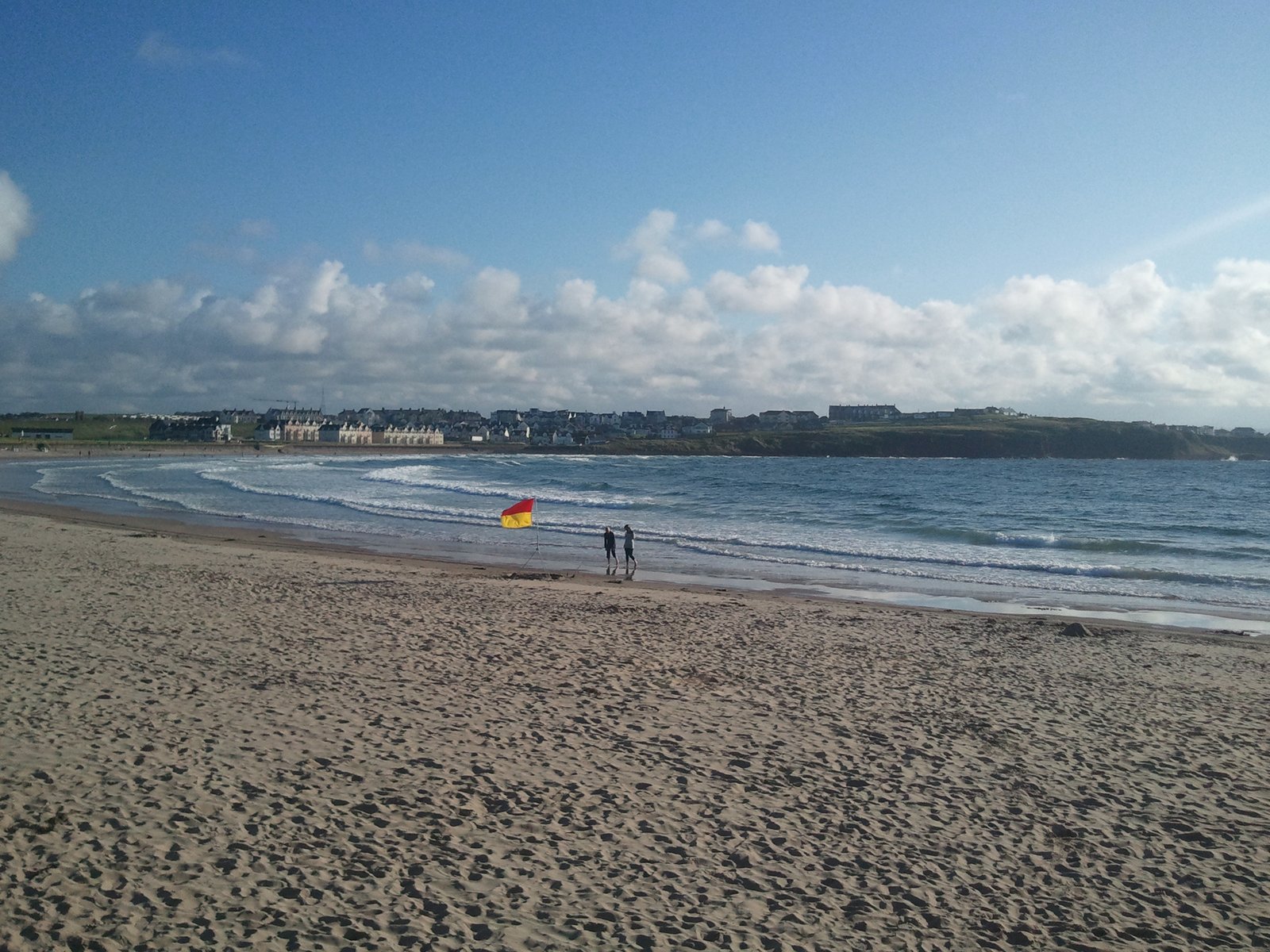 East Strand beach at Portrush with the town on the headland and surf rolling in