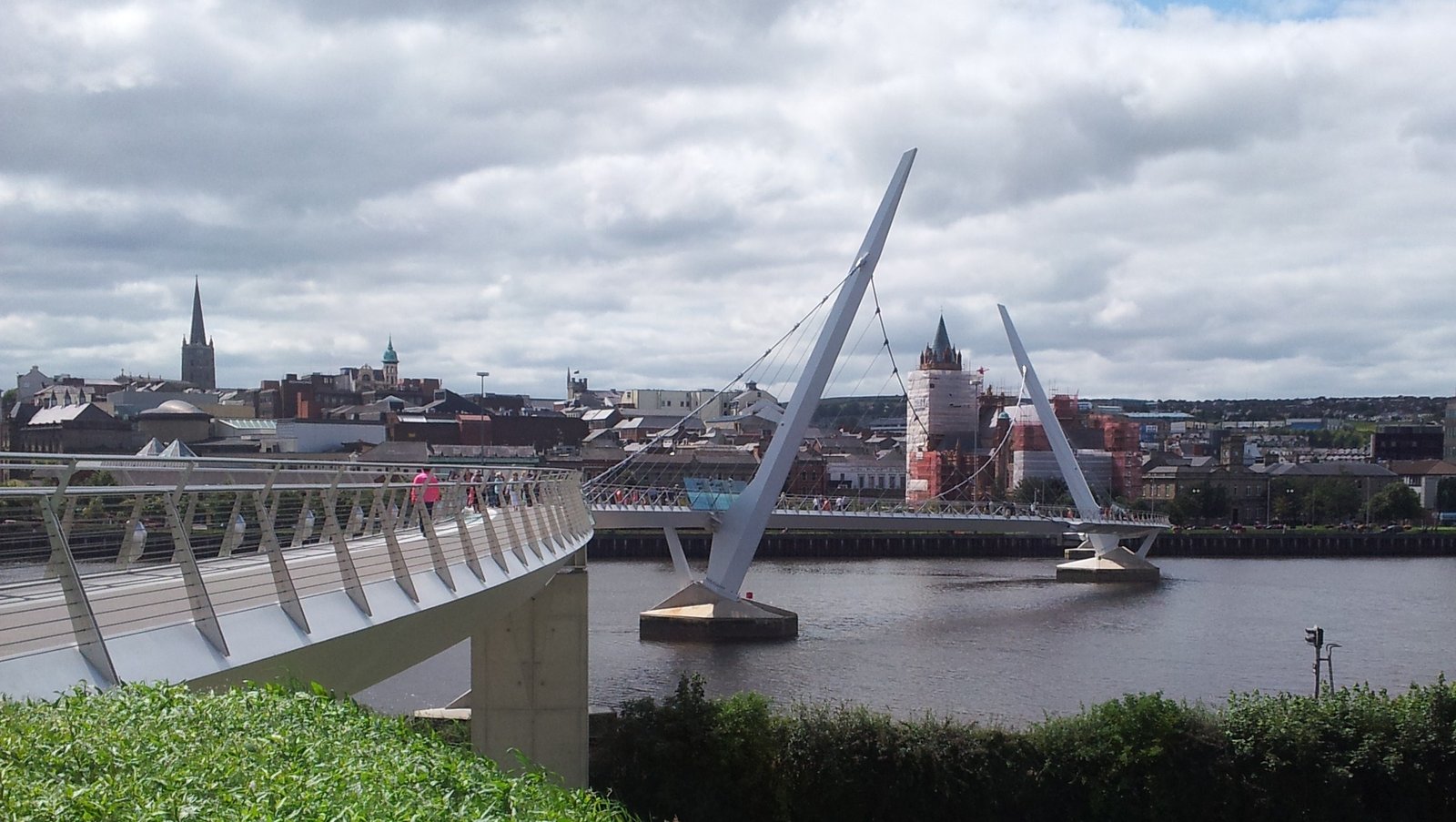 The Peace Bridge over the River Foyle with the Derry skyline and Guildhall behind it