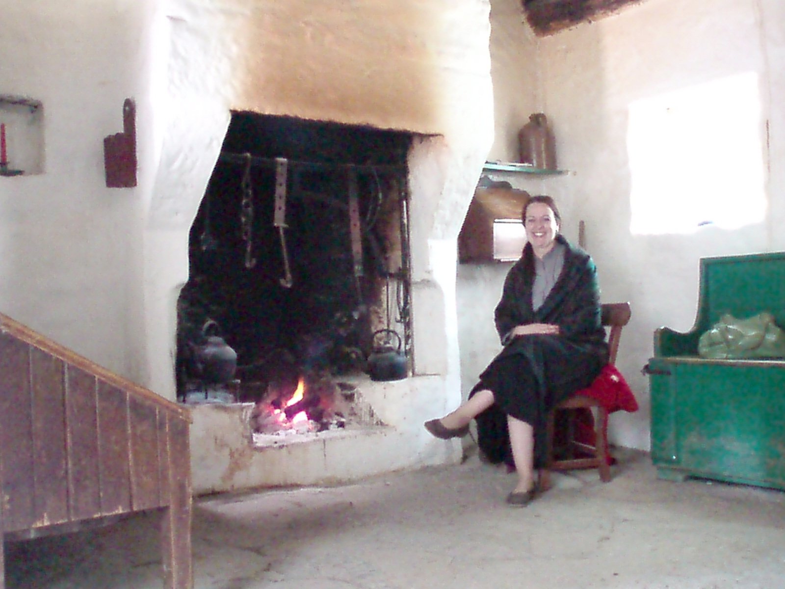 A costumed guide by the hearth inside a thatched cottage at the Ulster American Folk Park