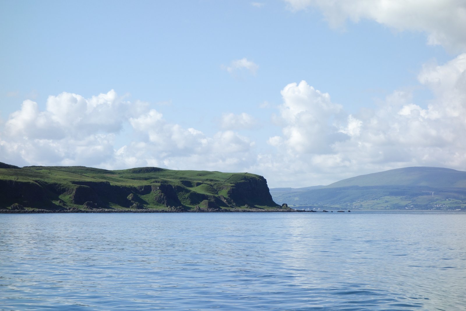 Green cliffs of Rathlin Island rising from the sea, seen from the approaching ferry