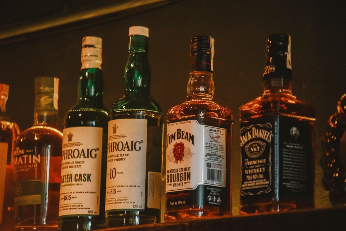 Row of whiskey bottles lit up along a pub back shelf