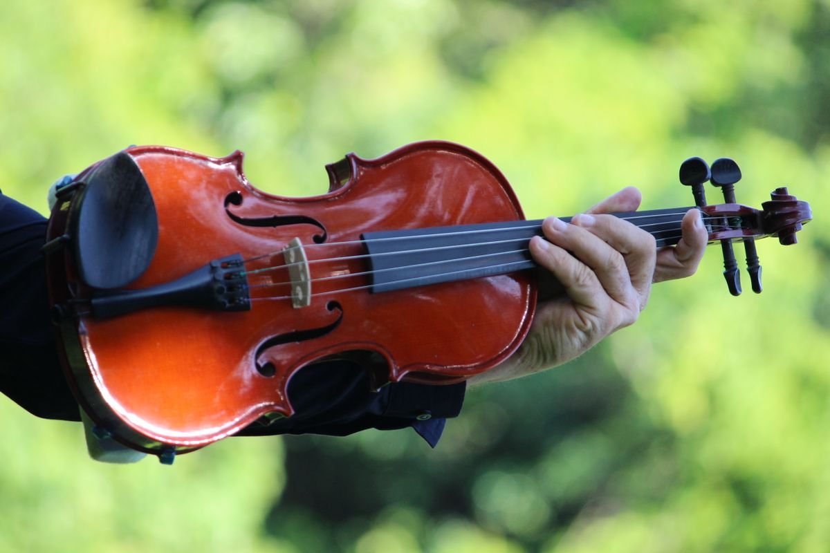 Hands playing a fiddle at a traditional Irish music session