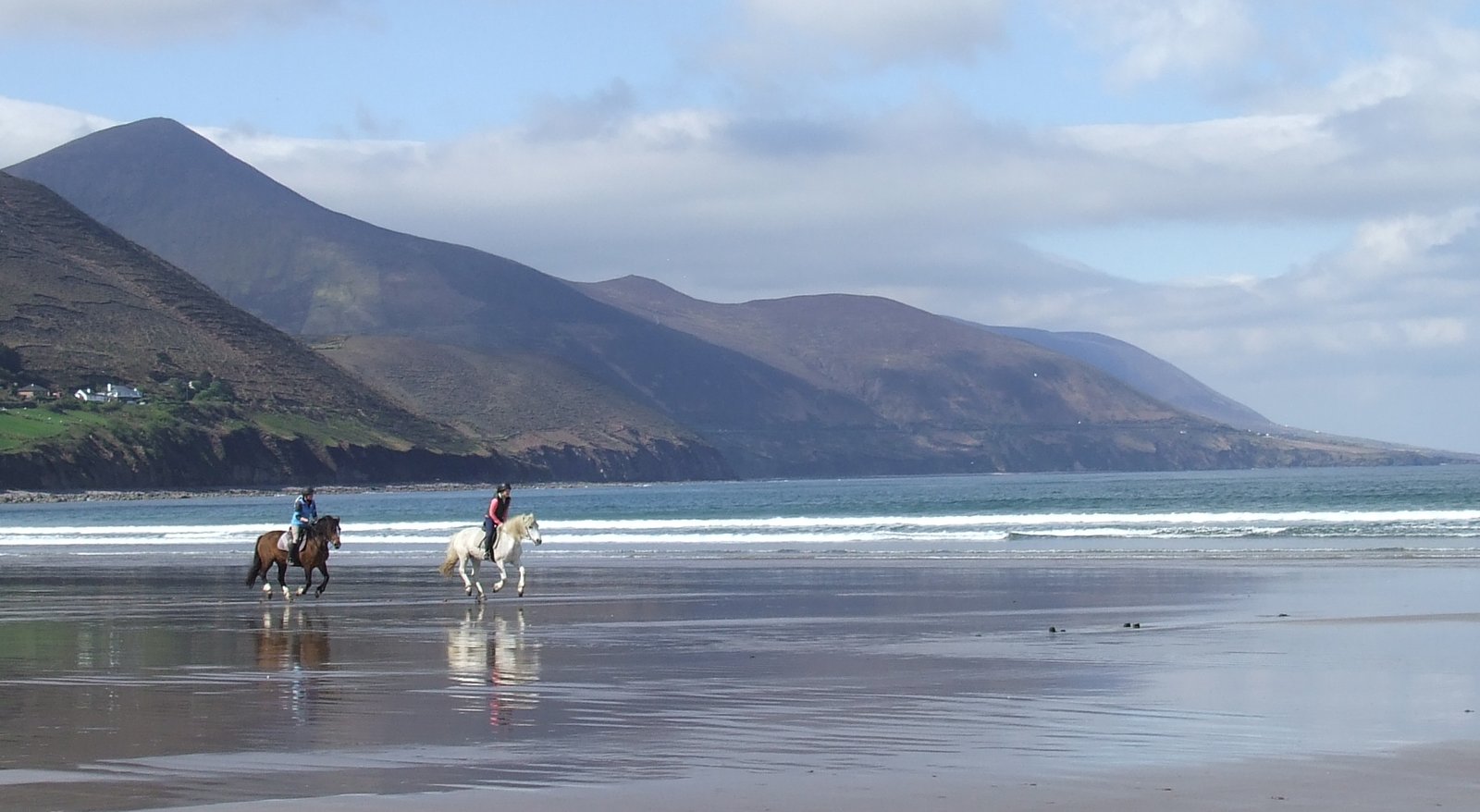 Horse riders on the flat sand at Rossbeigh with mountains across the water