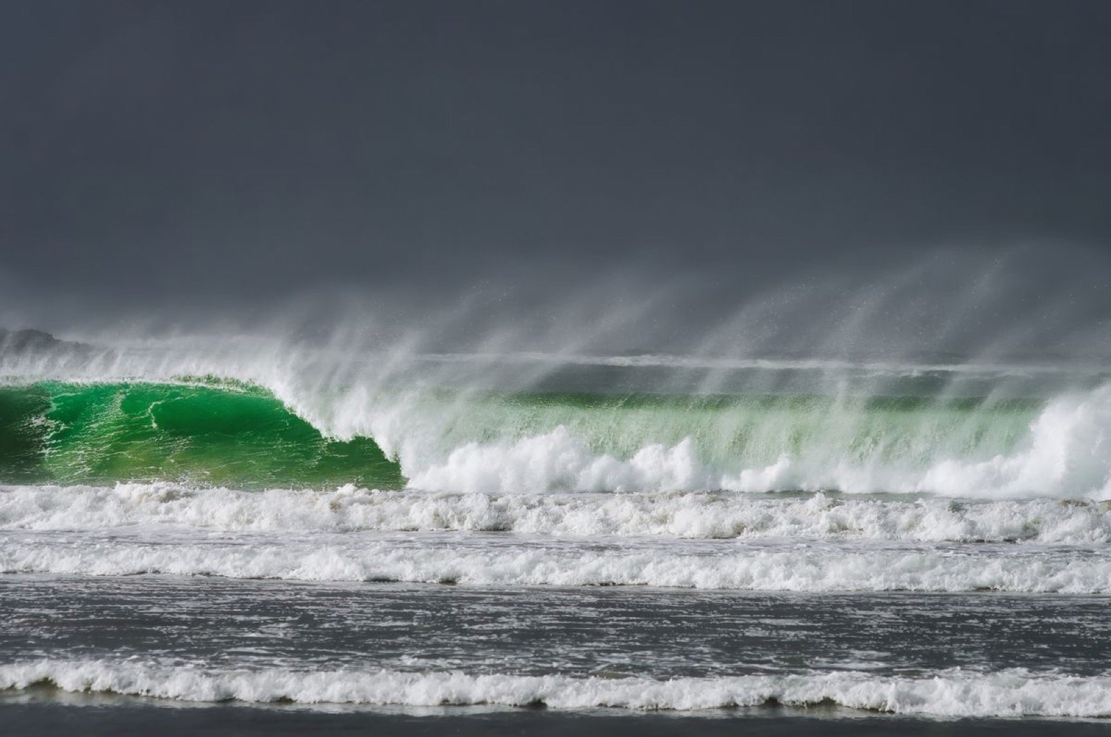 A large wave breaking under a dark stormy sky off the Atlantic coast