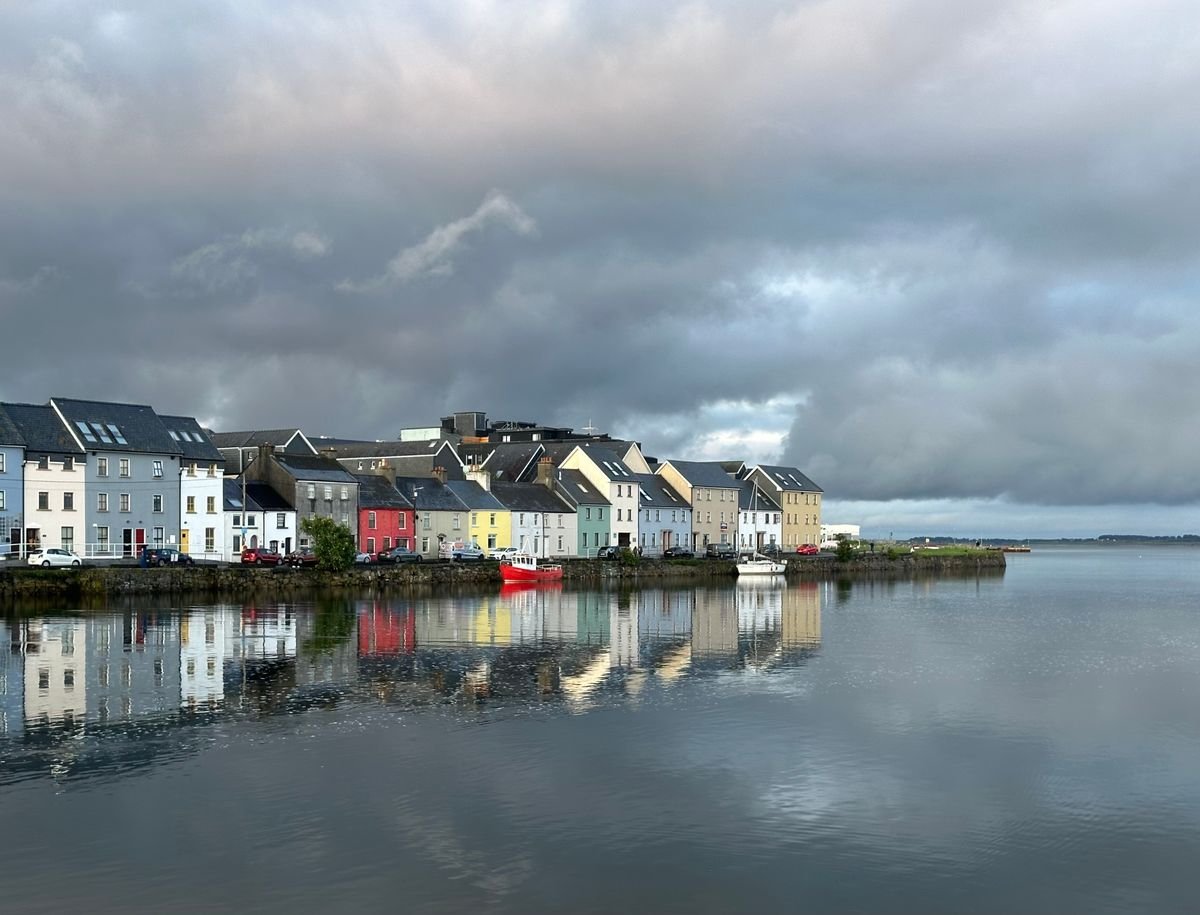 The colourful houses of the Long Walk in Galway reflected in calm water