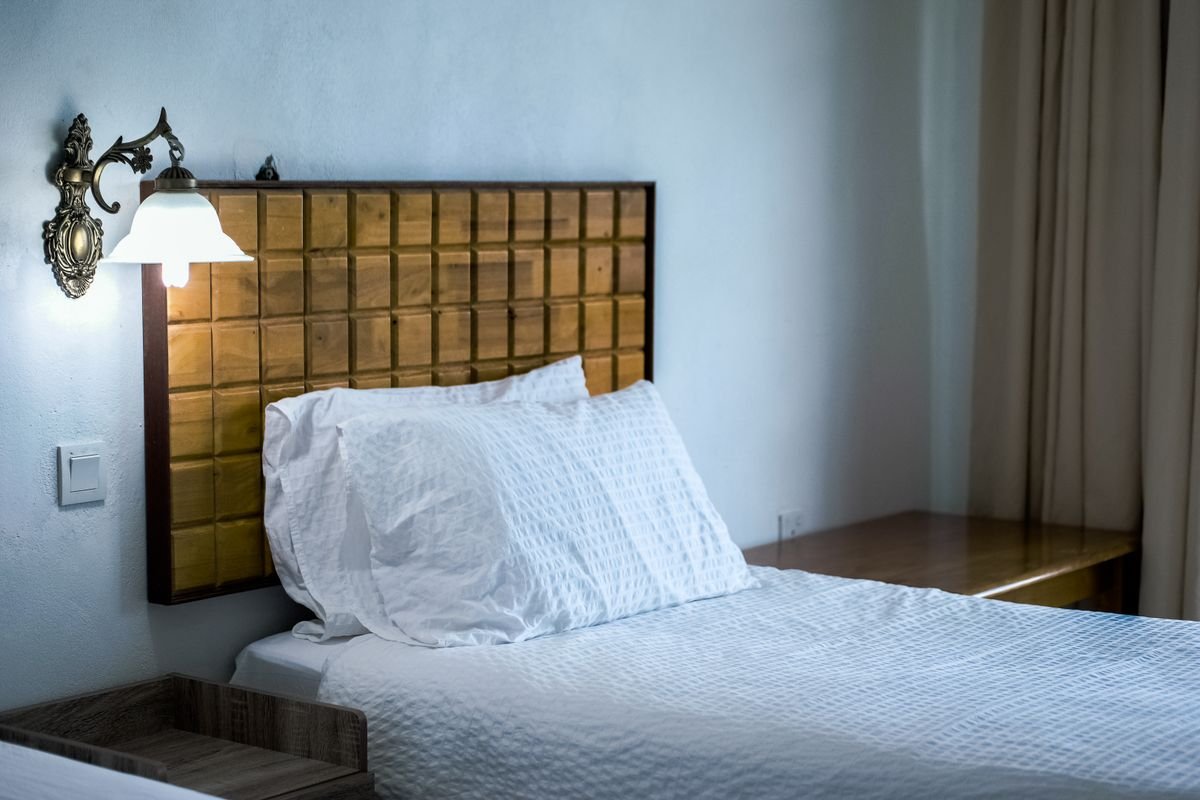 A tidy hotel room with white bedding and a warm bedside lamp