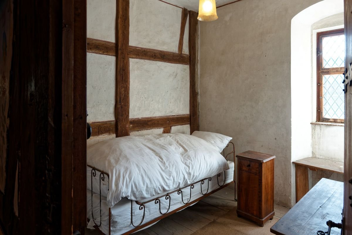 A rustic room with a wrought iron bed and whitewashed walls