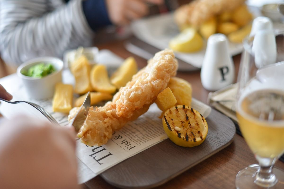 A plate of fish and chips with lemon on a wooden table