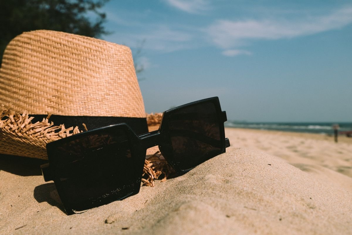 Sunglasses and a straw hat on a sandy beach