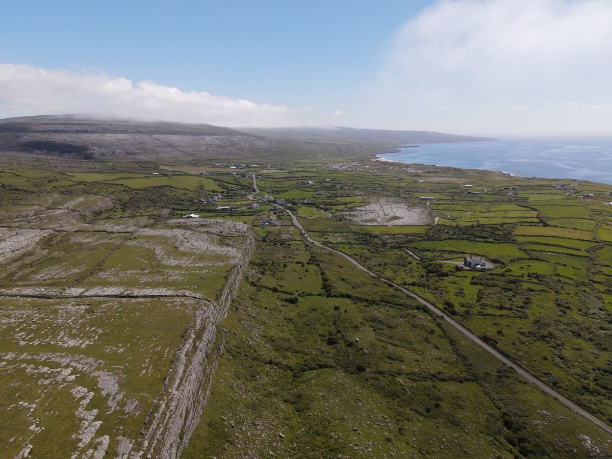 Coastal road winding through the Burren toward the sea in County Clare