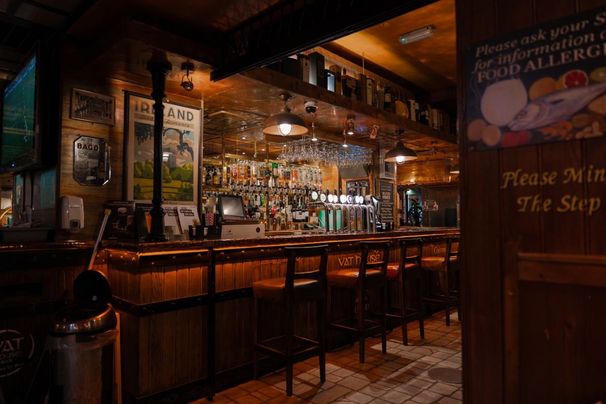 A warm traditional Irish pub interior with a wooden bar and stools