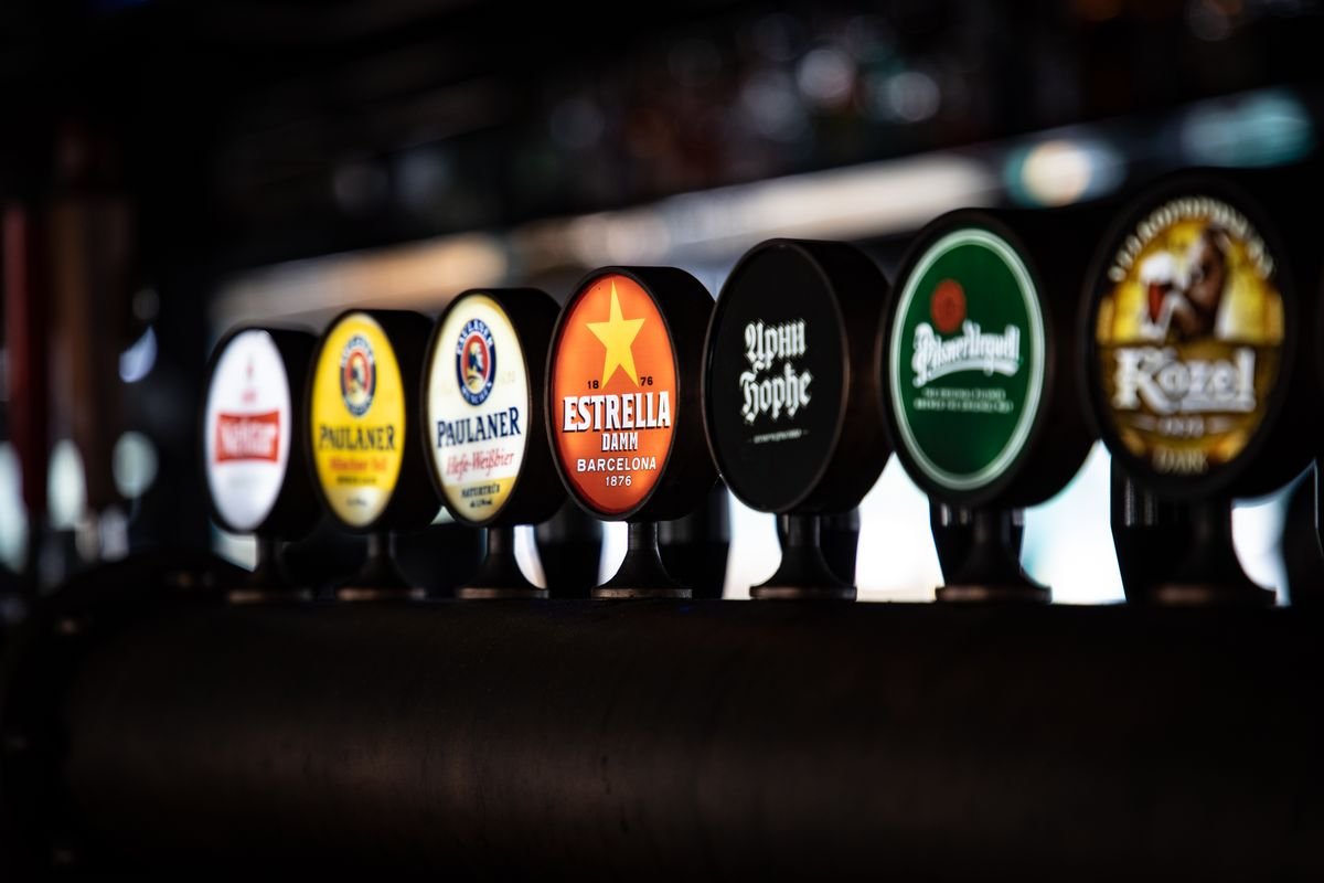 A row of lit beer taps along a pub bar