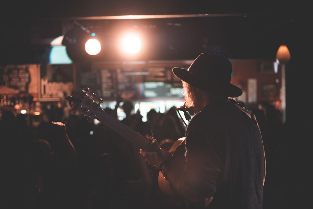 A guitarist playing to a crowd in a late-night music venue