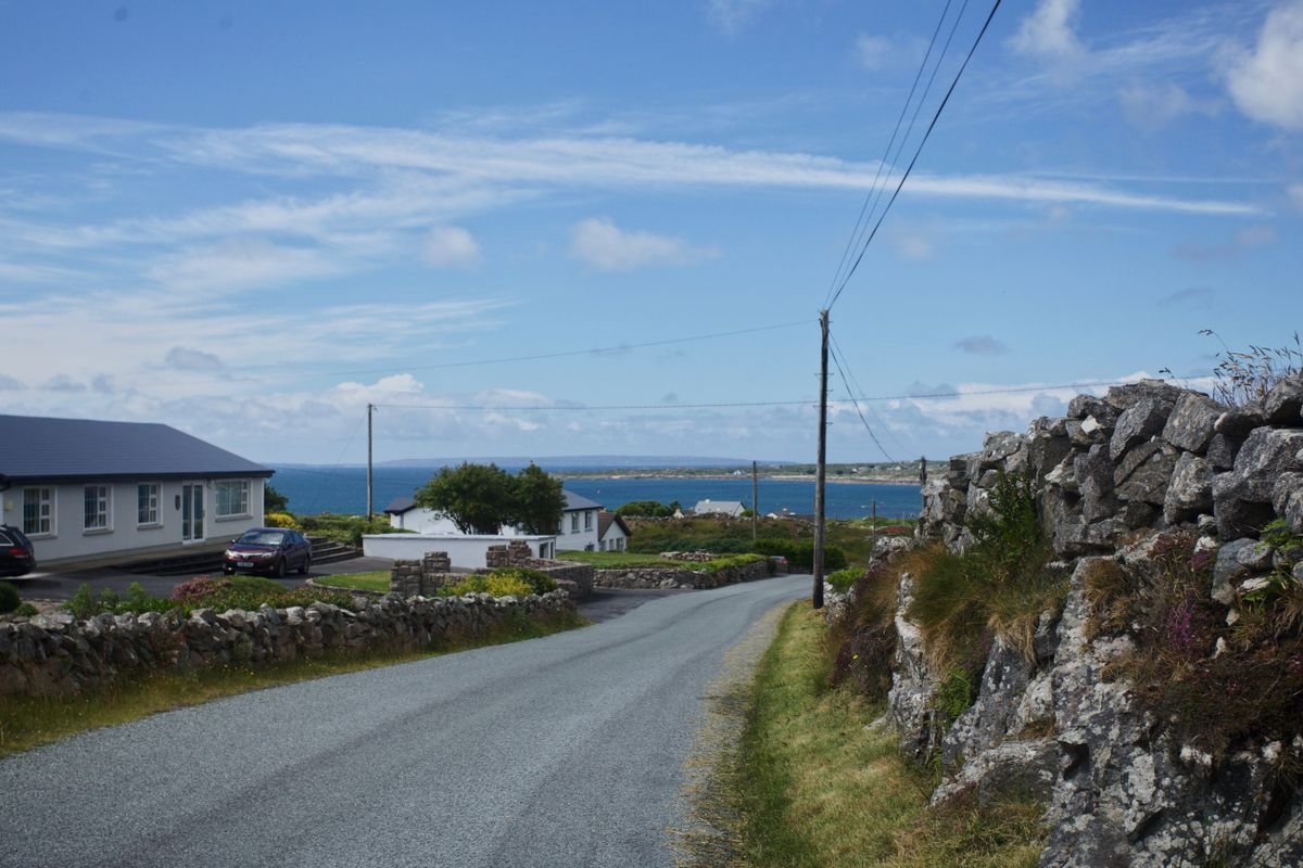 A narrow coastal road with a stone wall and sea view in the west of Ireland