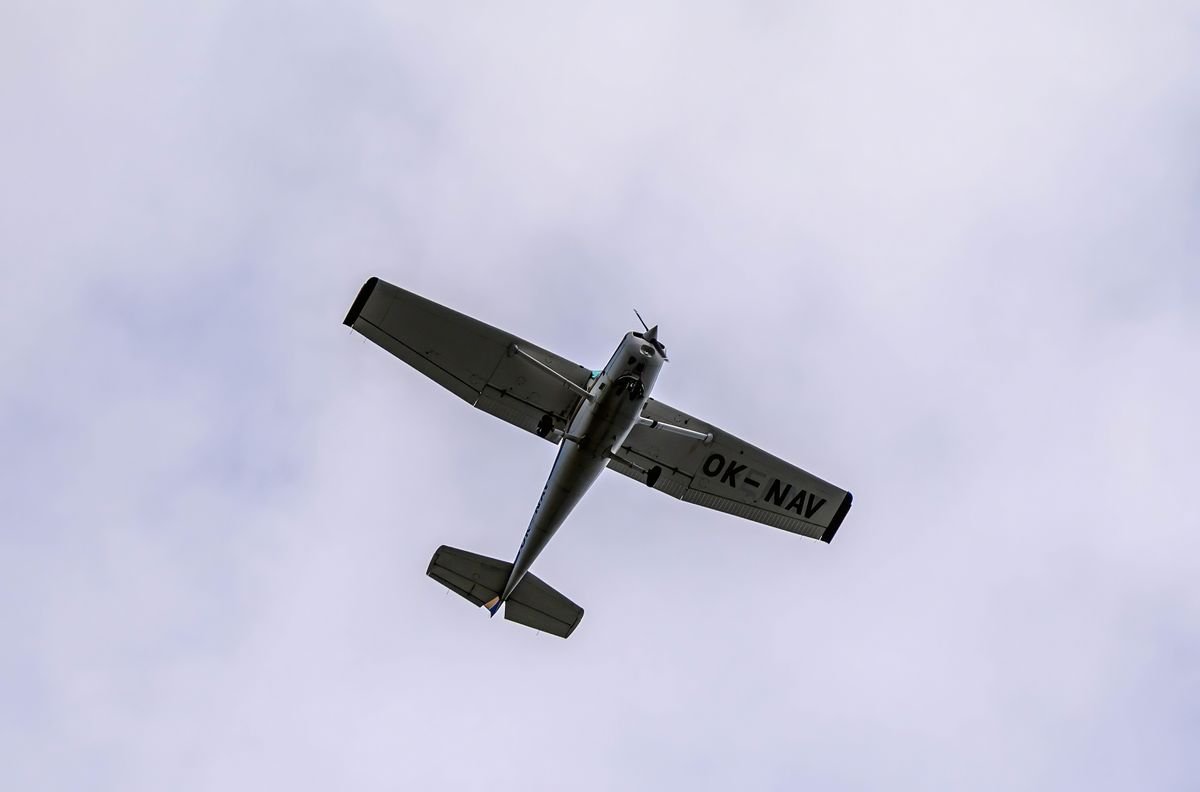 A small propeller plane in flight against a grey sky