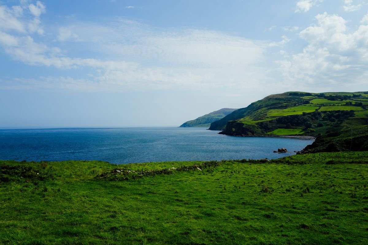 Green coastal headland over calm blue sea in Ireland