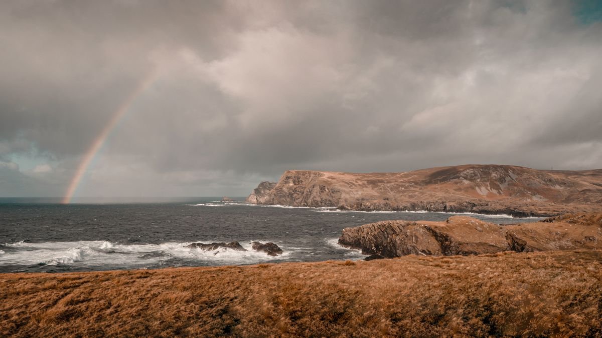 Rainbow over a moody windswept Irish coastline