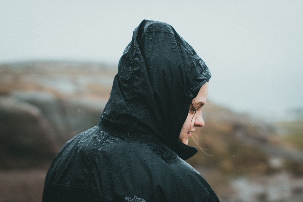 A person in a black rain jacket on a misty Irish headland
