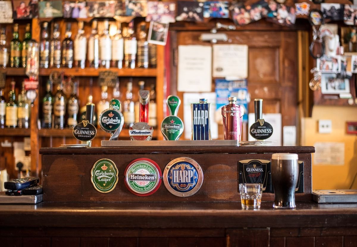 Wooden pub back bar with beer taps and a pint of stout on the counter
