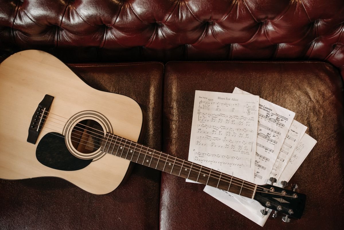 An acoustic guitar and sheet music ready for a late session