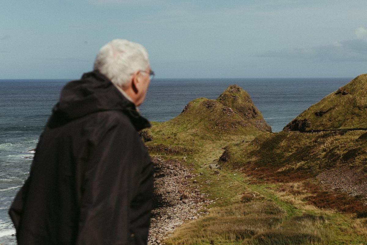 A visitor in a rain jacket looking out over a rugged Irish landscape