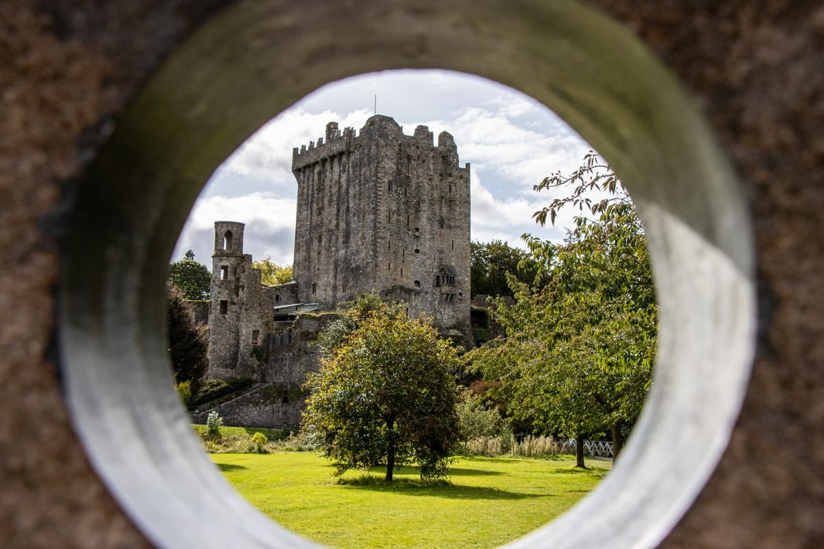Blarney Castle tower and grounds framed through a round stone opening