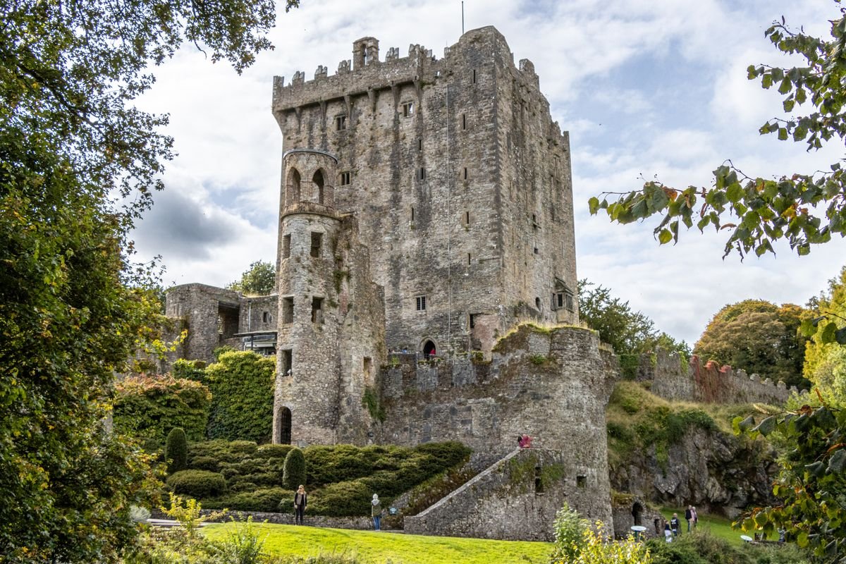 Blarney Castle tower rising above the grounds with visitors at the base