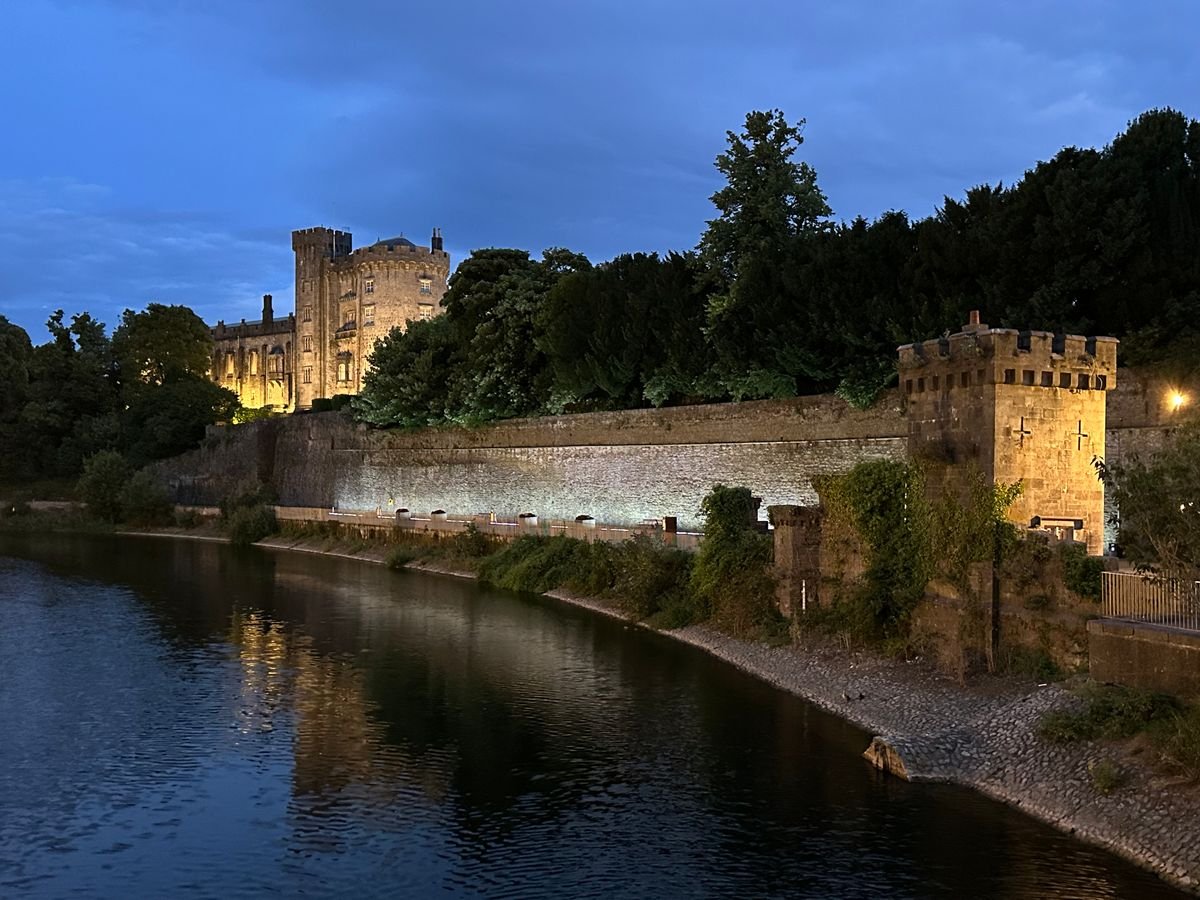 Kilkenny Castle lit over the river at dusk