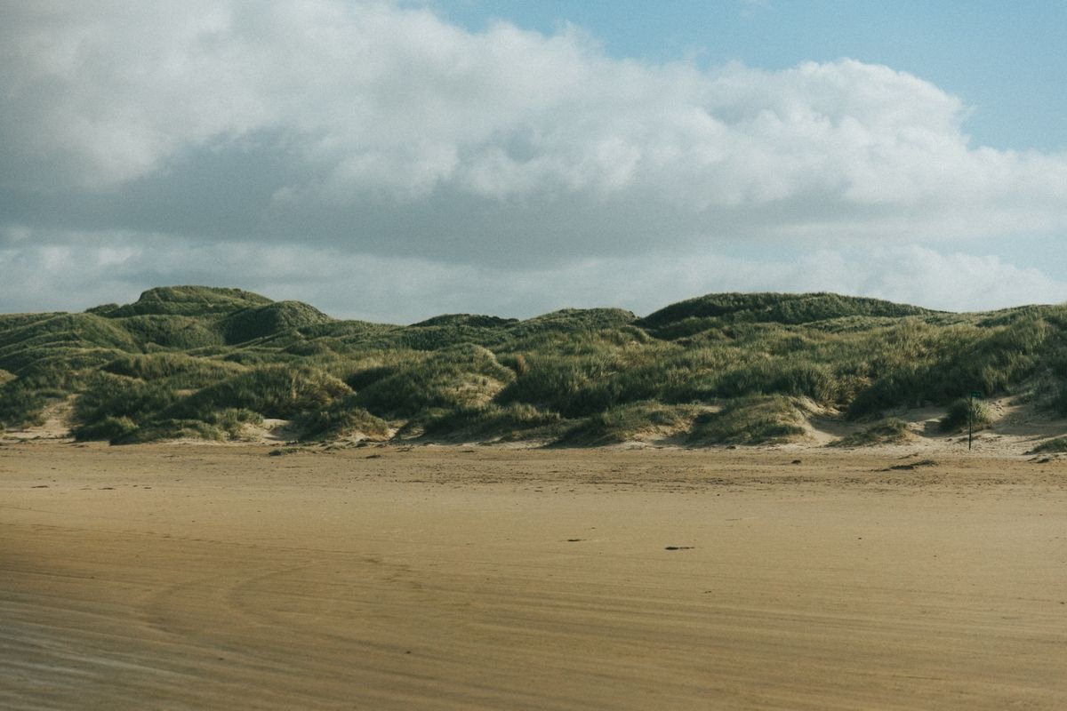 Green marram dunes above a wide empty sand beach in Donegal
