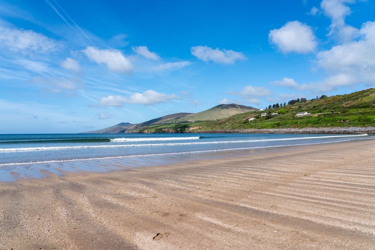 Wide sandy Kerry beach on a clear day with blue sky and mountains behind