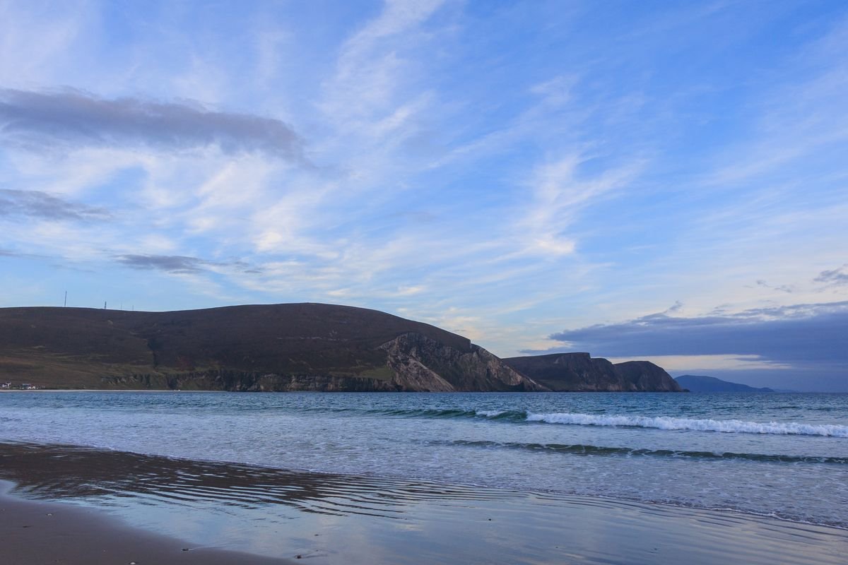 Silver Strand beach in County Mayo, pale sand and Atlantic waves with a headland behind