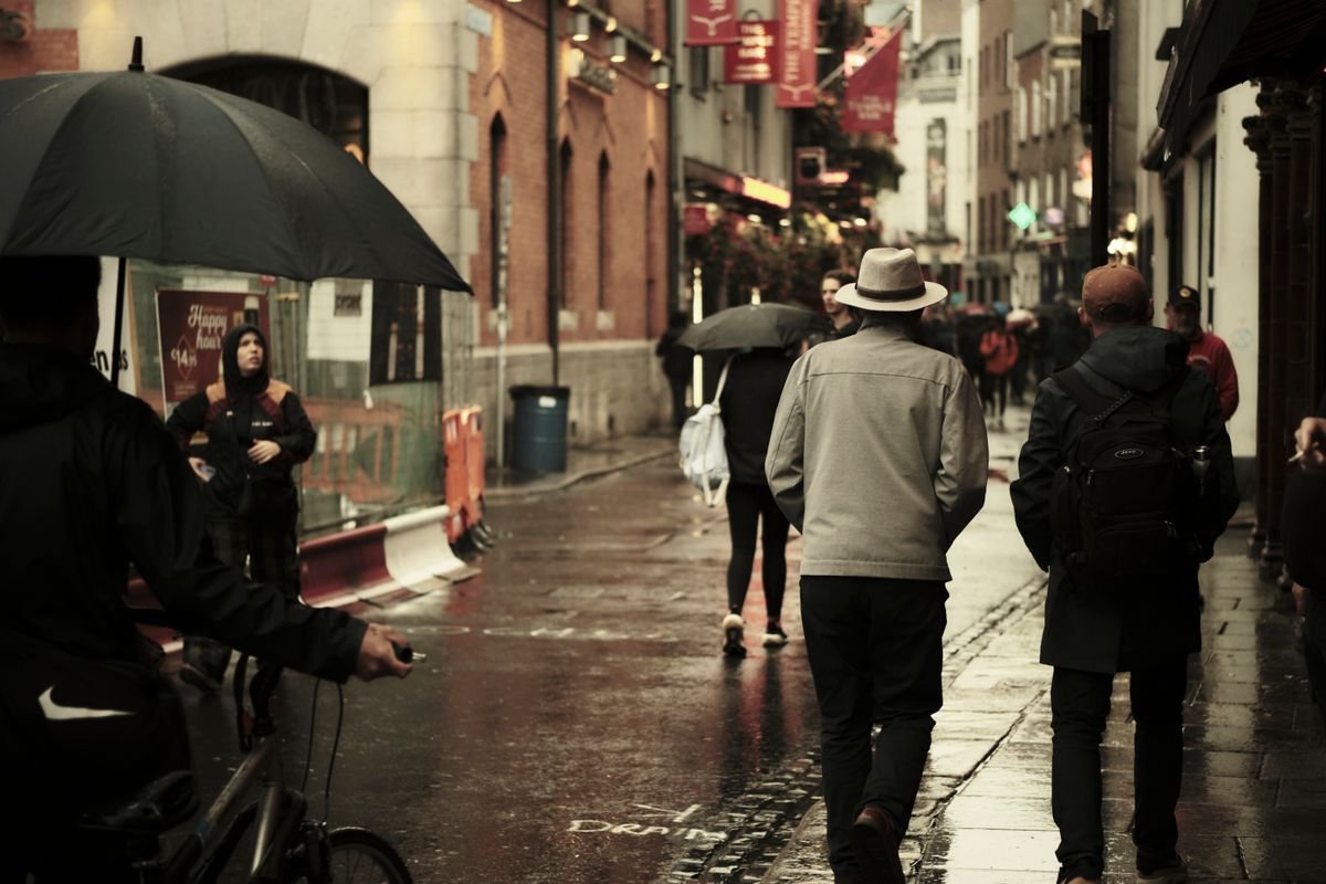People walking a rainy Dublin street in Temple Bar with umbrellas and rain jackets