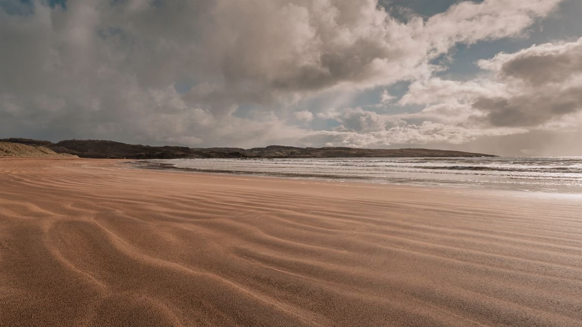 Wind-rippled golden sand on a Donegal Atlantic beach under a moody sky