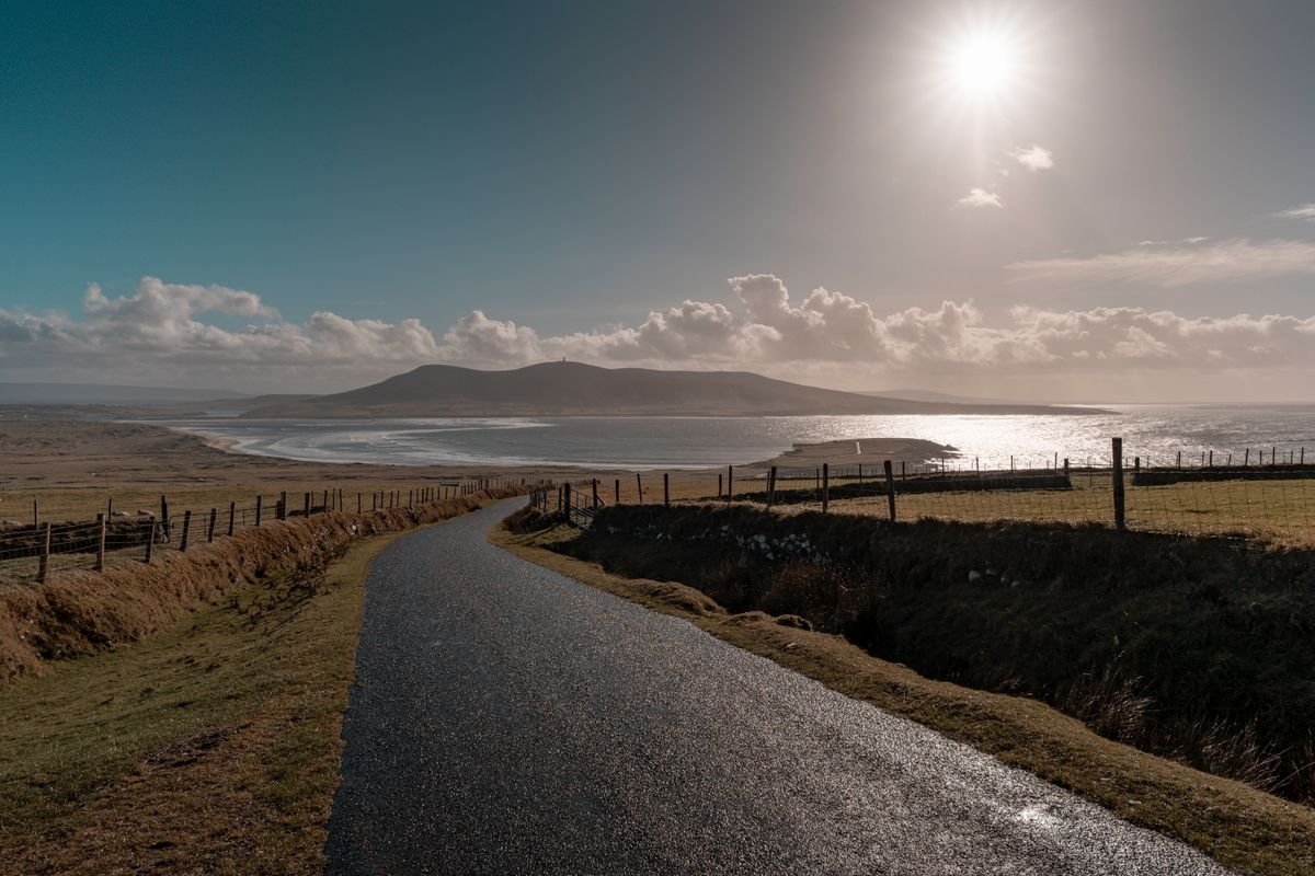 A coastal road curving toward an Atlantic beach and mountain in the west of Ireland