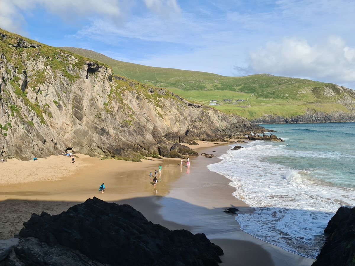 Sheltered sandy cove near Louisburgh in County Mayo with green headlands and calm water