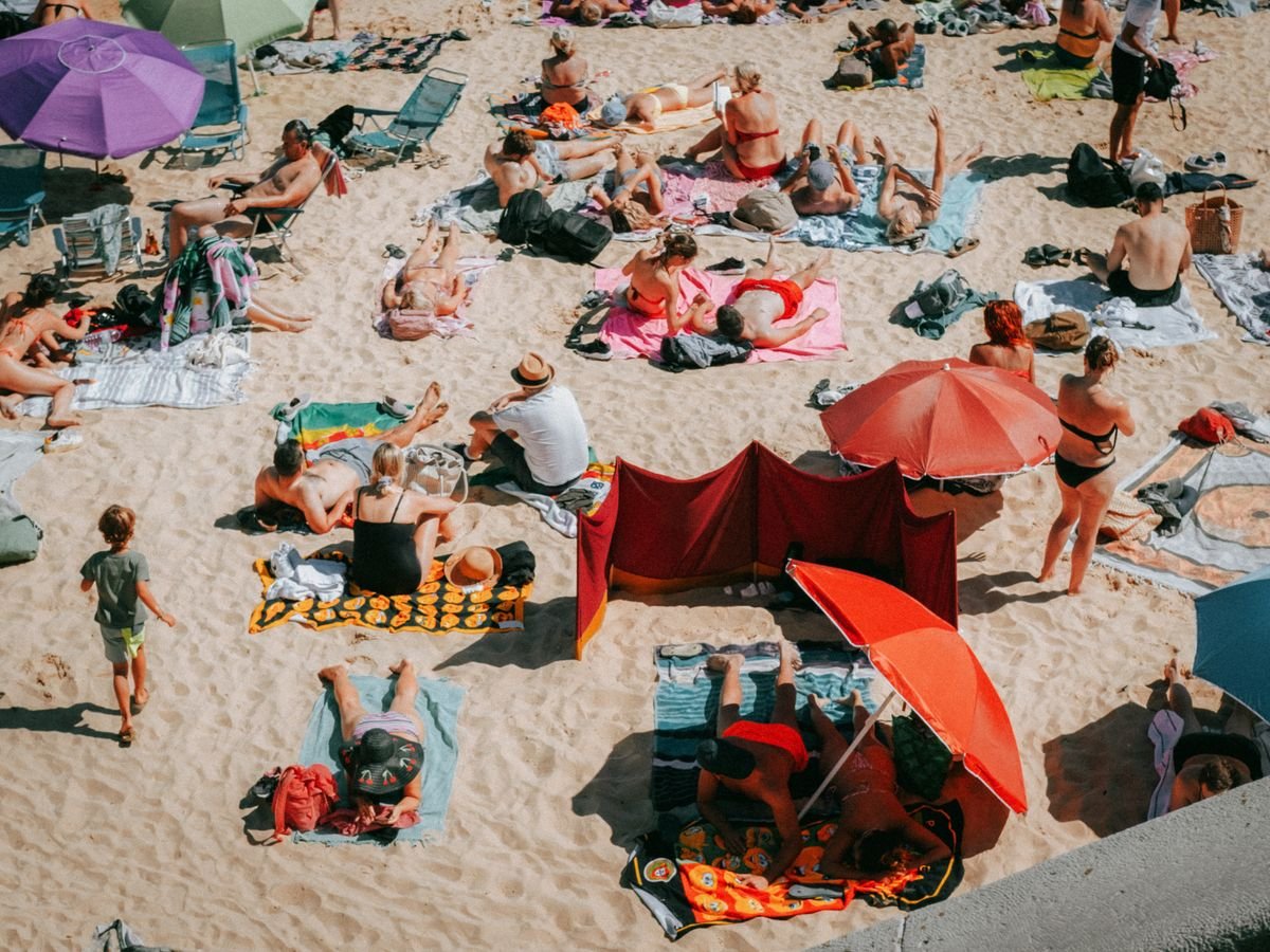 Crowded sandy beach packed with sunbathers and umbrellas on a summer day