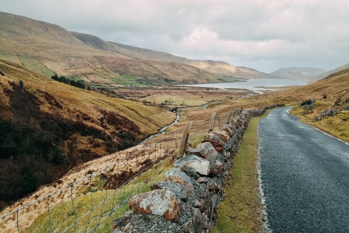 Narrow rural road with a stone wall running along the hills in Donegal