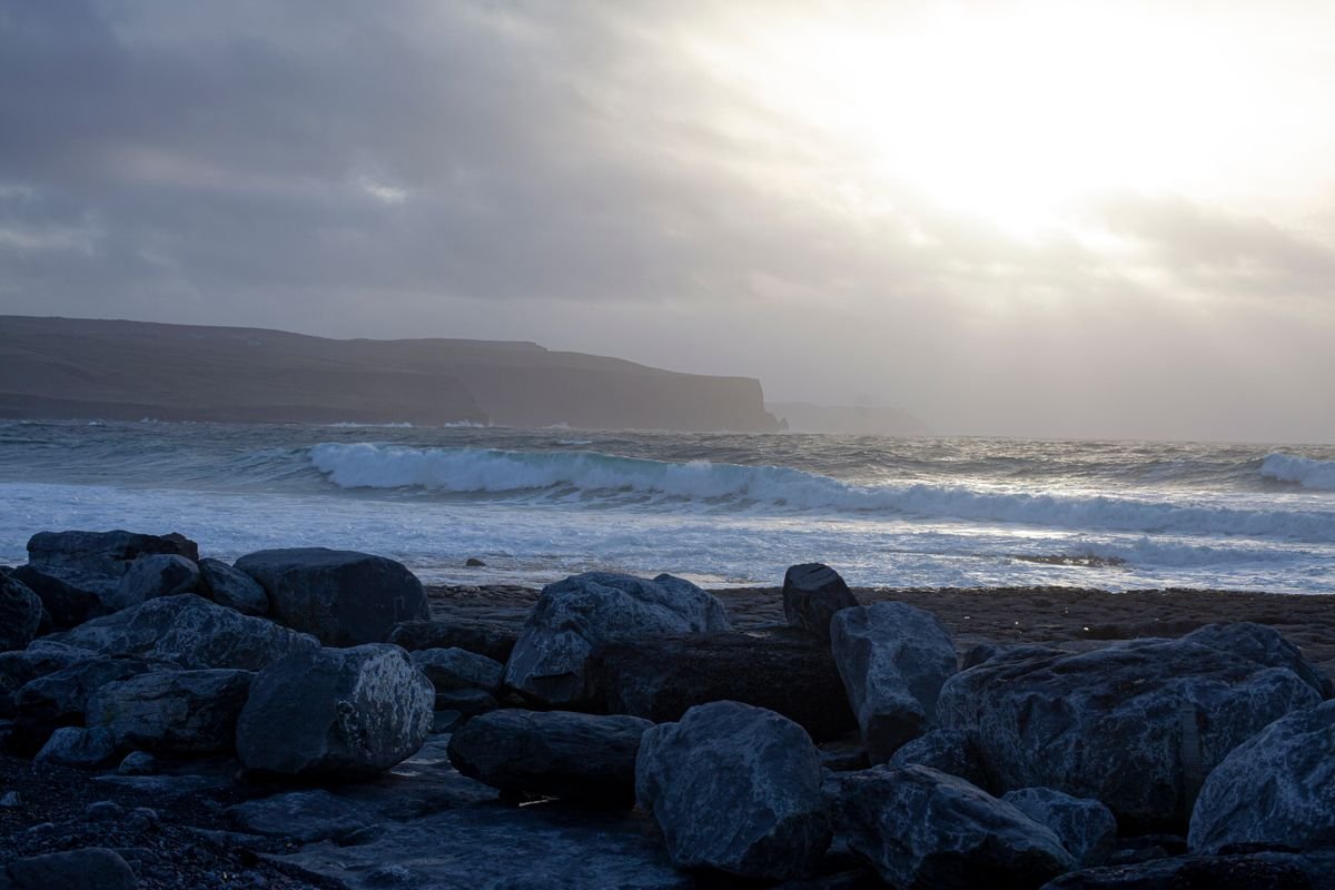 Waves breaking below cliffs under a stormy sky on the Clare coast