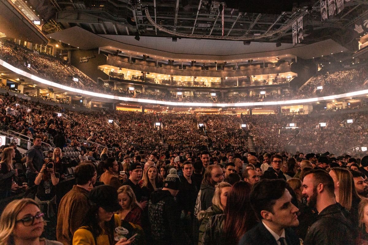 A packed indoor arena crowd under the lighting ring during a concert