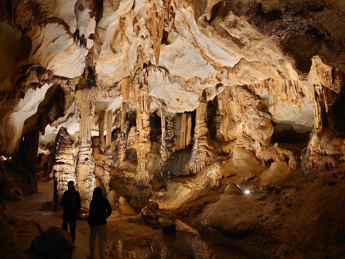 A lit path through a limestone show cave past stalactites and stalagmites