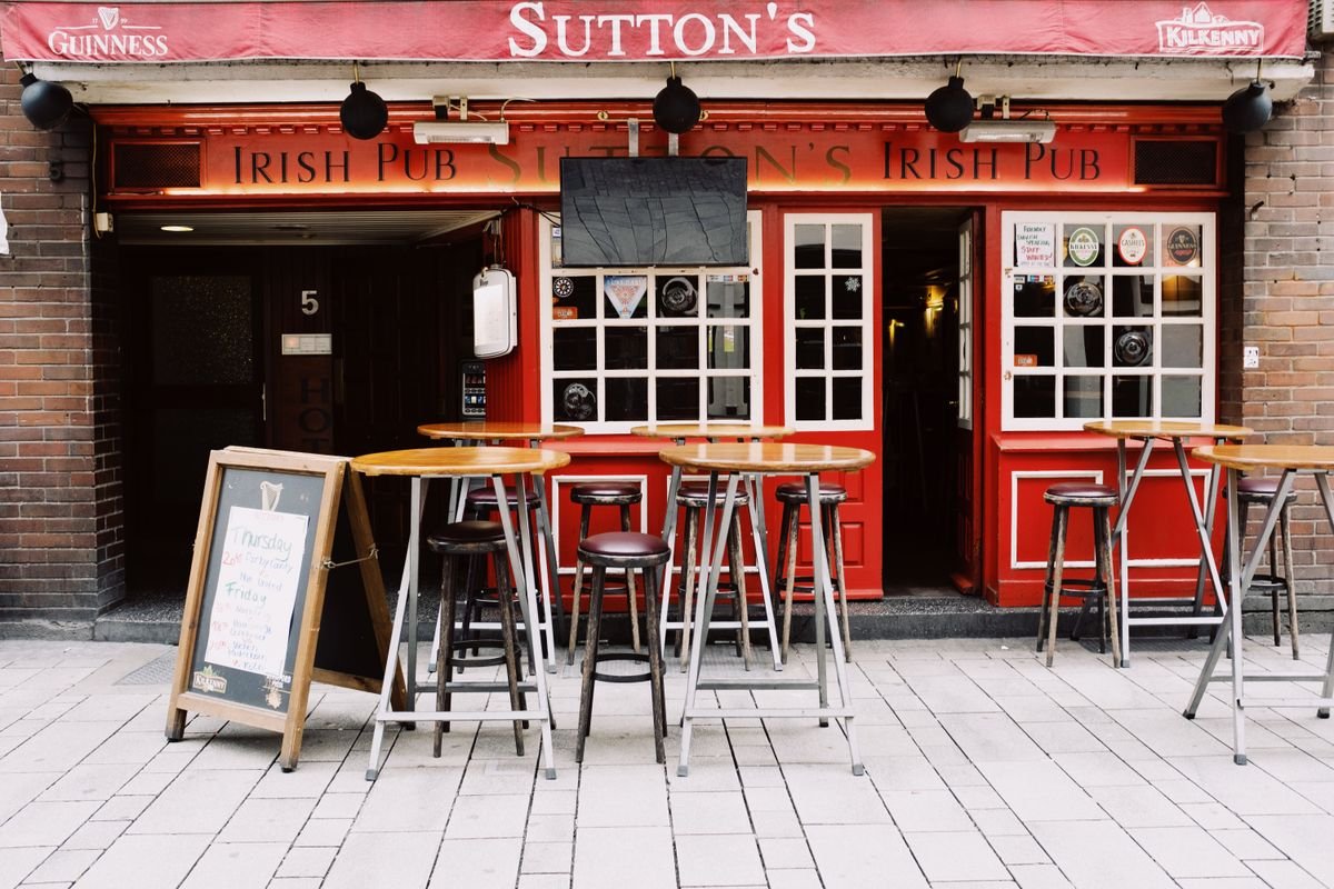 Red-painted Irish pub exterior with tables and stools out front