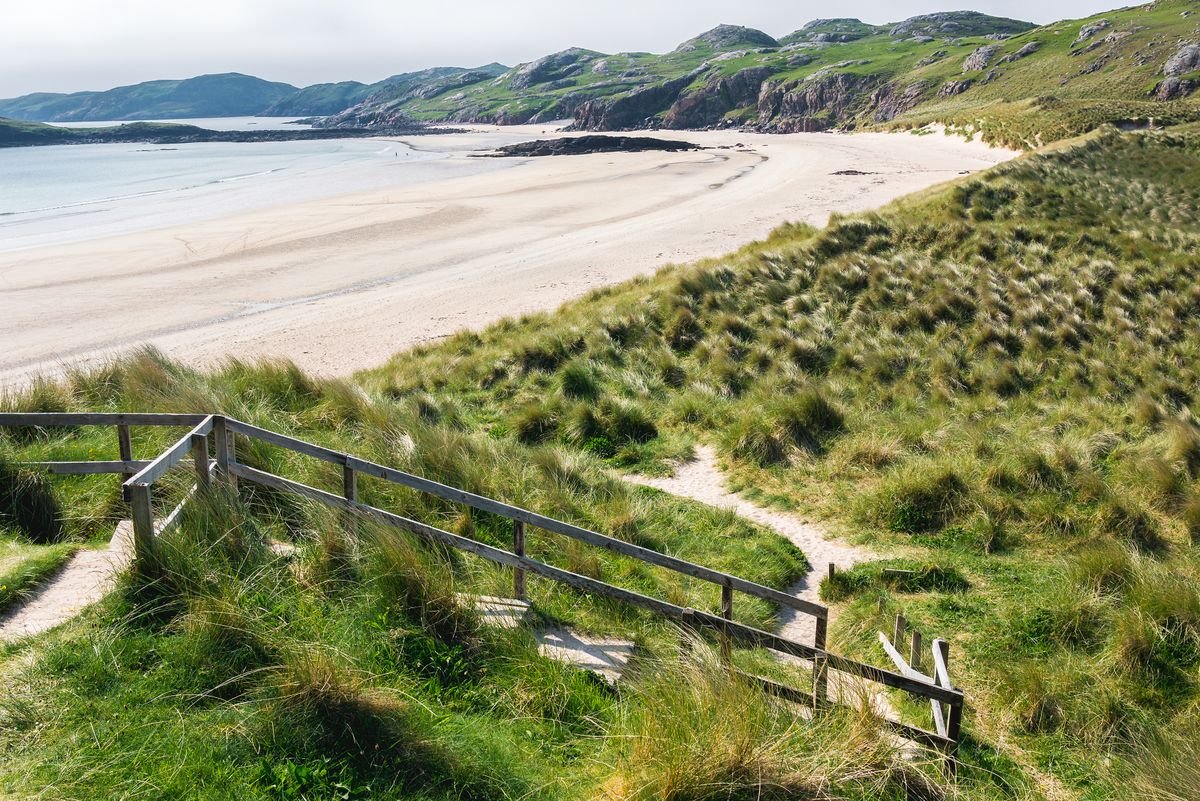 A path down through dune grass to a sheltered white-sand cove in Donegal