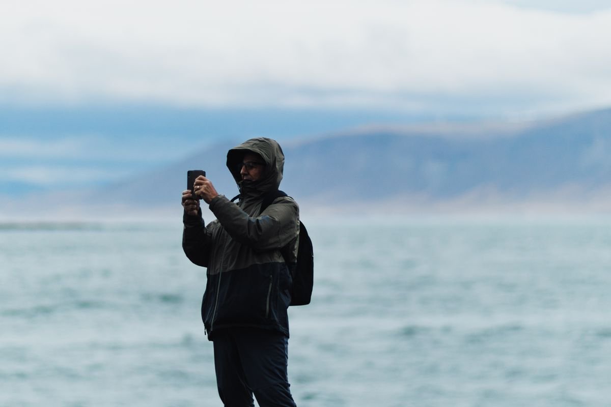 Person in a hooded rain jacket on a windy coast